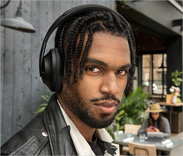 Tech gift ideas for dad - A man in an outdoor space wearing the black variant of the Bose Noise Cancelling Headphones 700