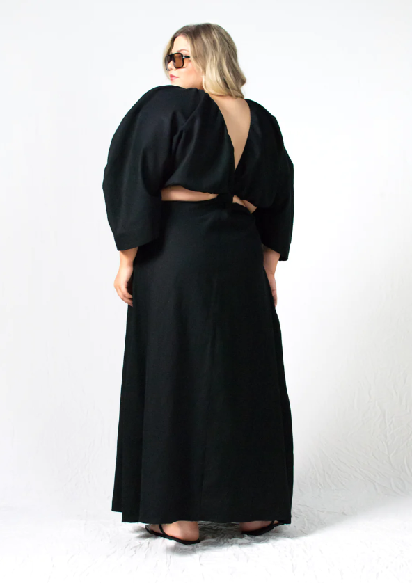 Sustainable apparel companies example - Woman wearing sunglasses and a long black dress with cutouts is seen from the back.
