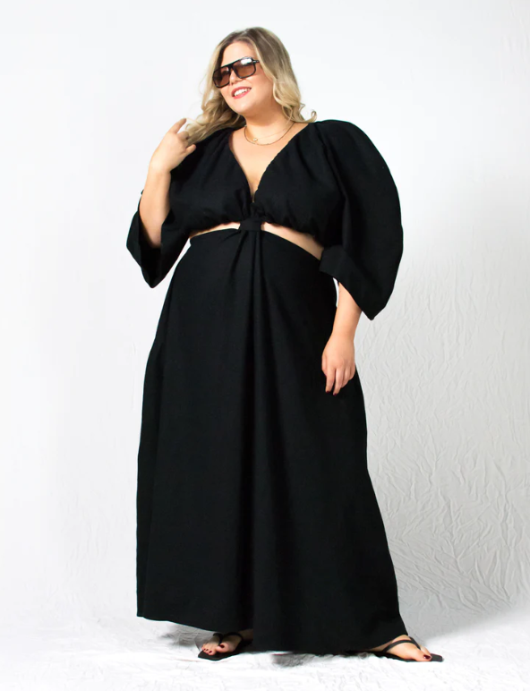 Sustainable apparel companies example - Woman wearing sunglasses and a long black dress with cutouts in the midriff section.
