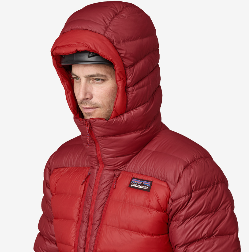 Man in a red down jacket with the hood up. Patagonia logo is attached on the left chest area of the jacket.