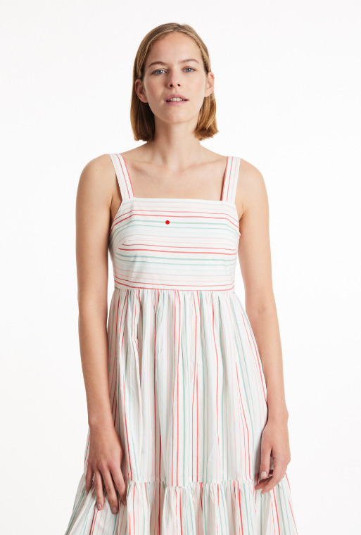 Sustainable apparel companies example - Woman in a sleeveless dress featuring multicolored stripes and a tiered skirt.