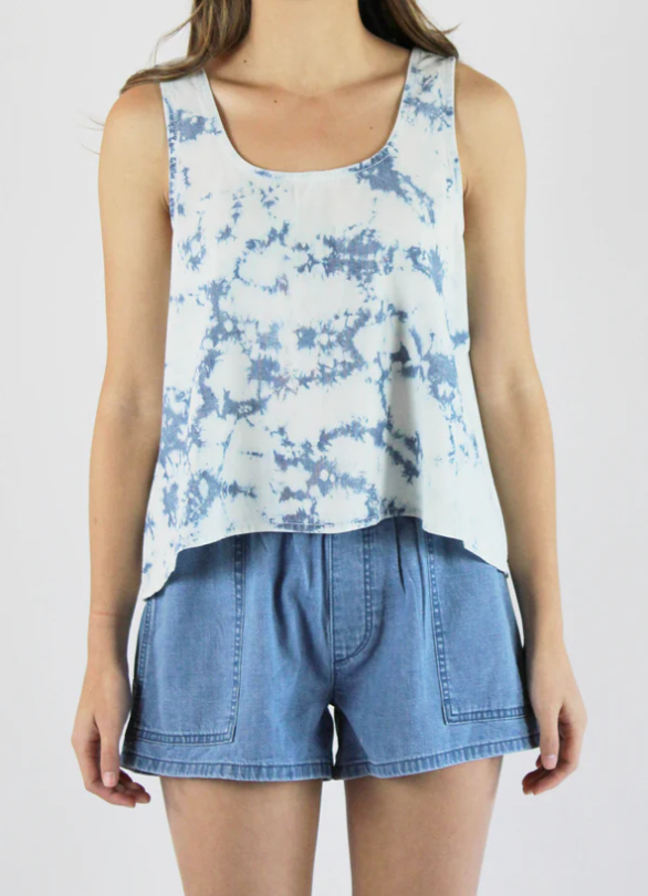 Sustainable apparel companies example - Mid-section of a woman wearing a blue tie dye tank top and chambray shorts.