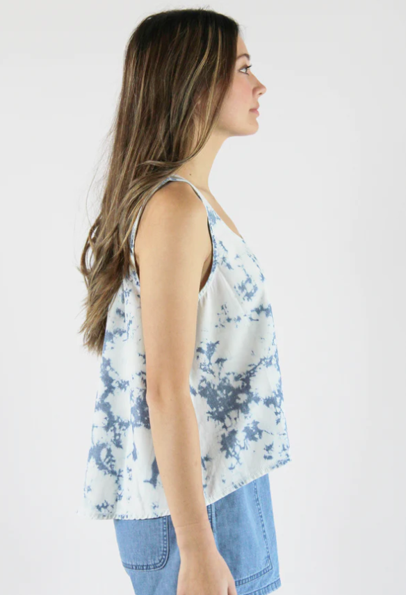 Sustainable apparel companies example - Side view of a woman wearing a blue tie dye tank top and chambray shorts.