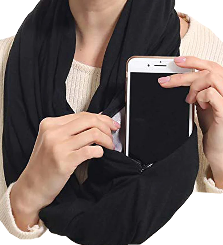 Woman holding phone in black neck scarf's zipper pocket.