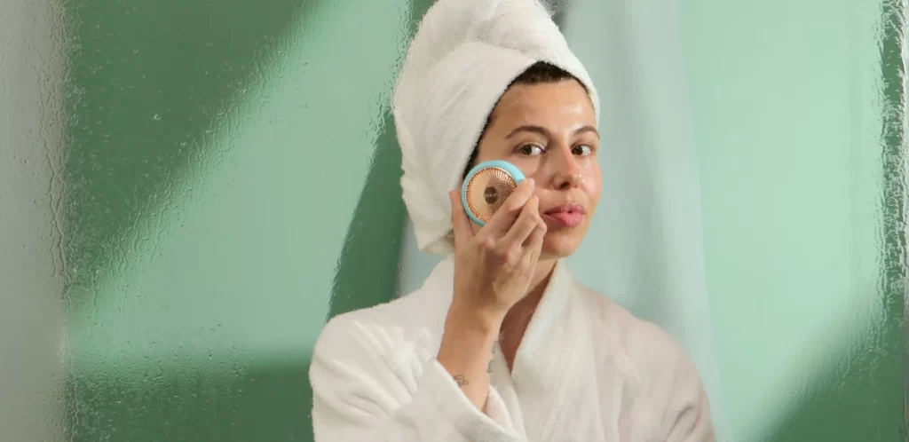 Bathrobe-clad woman using FOREO Sweden's UFO™ 2 for face massage.