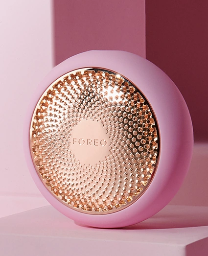 A pink and gold ball on a pink surface - FOREO Sweden's UFO™ 2, a beauty device for skincare treatments.