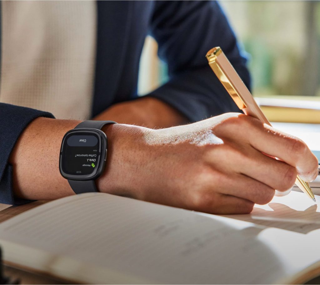 A man wearing Fitbit Sense 2, an affordable fitness tracker, while studying.