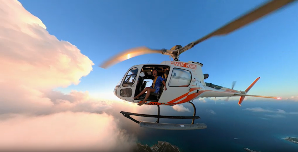 The Insta360 X3 action Camera captures a helicopter gliding over an ocean of clouds, with people on board.