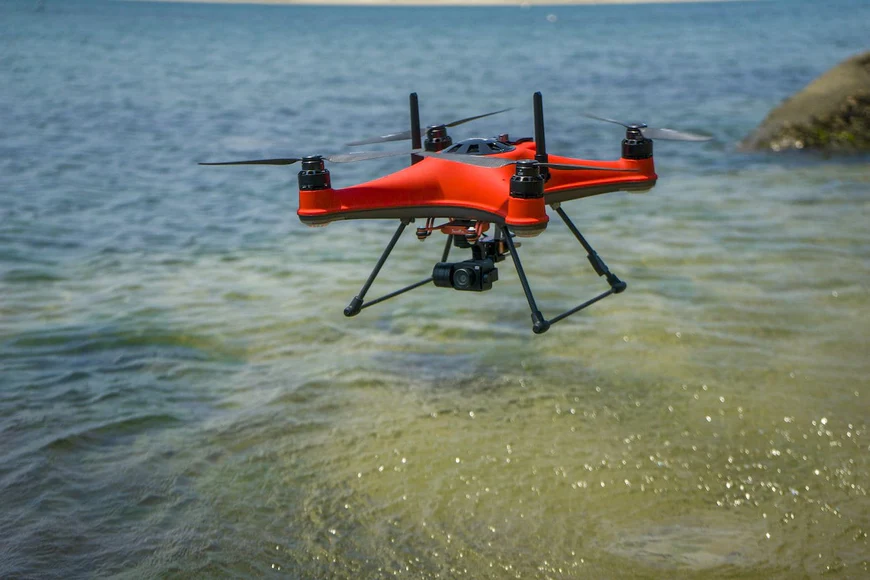 Behold the mesmerizing sight of a red drone, the Splash Drone 4 by SwellPro, gliding effortlessly over the vast expanse of the ocean.
