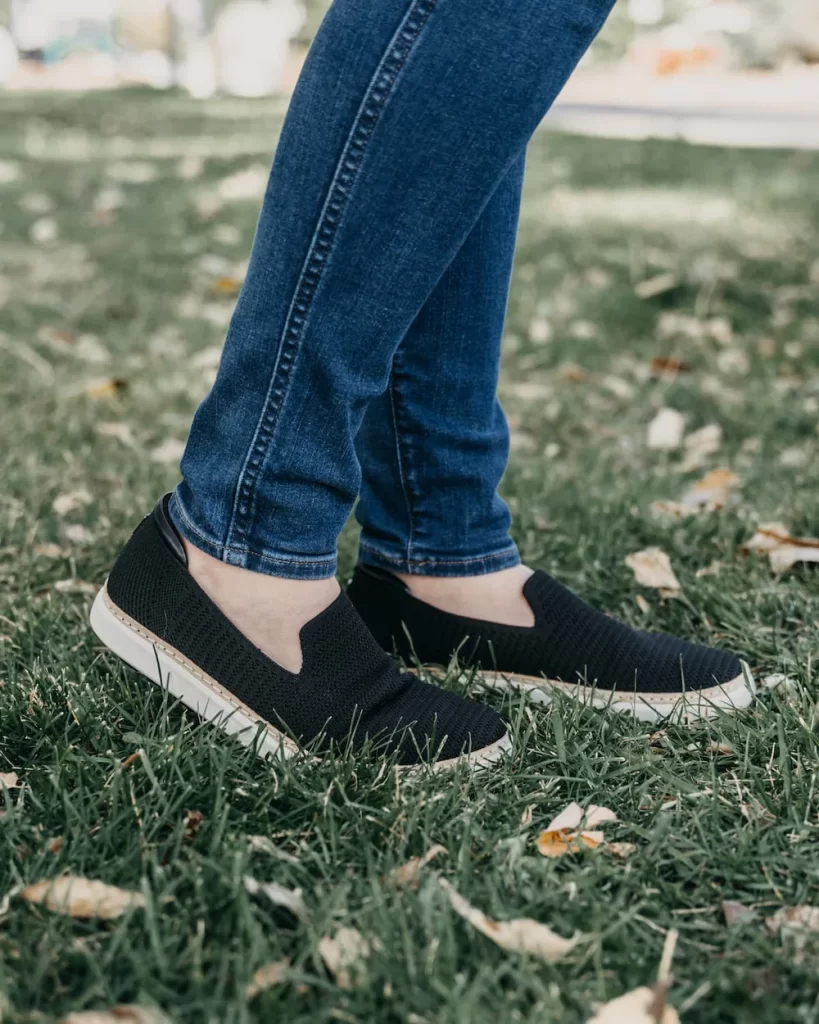 Black slip-on sneakers on grass.