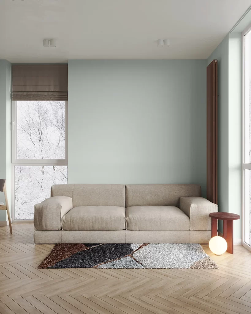 Contemporary living room with a couch and window, featuring a soothing pale grey-green wall color.