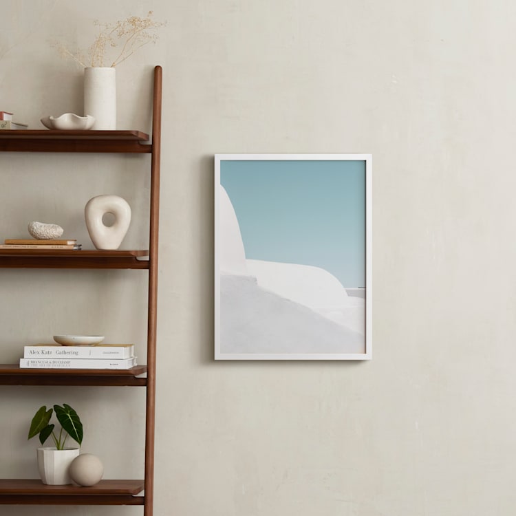 Framed architectural art print depicting white Cycladic buildings in Oia, Greece, styled as unique personalized gifts for home décor.